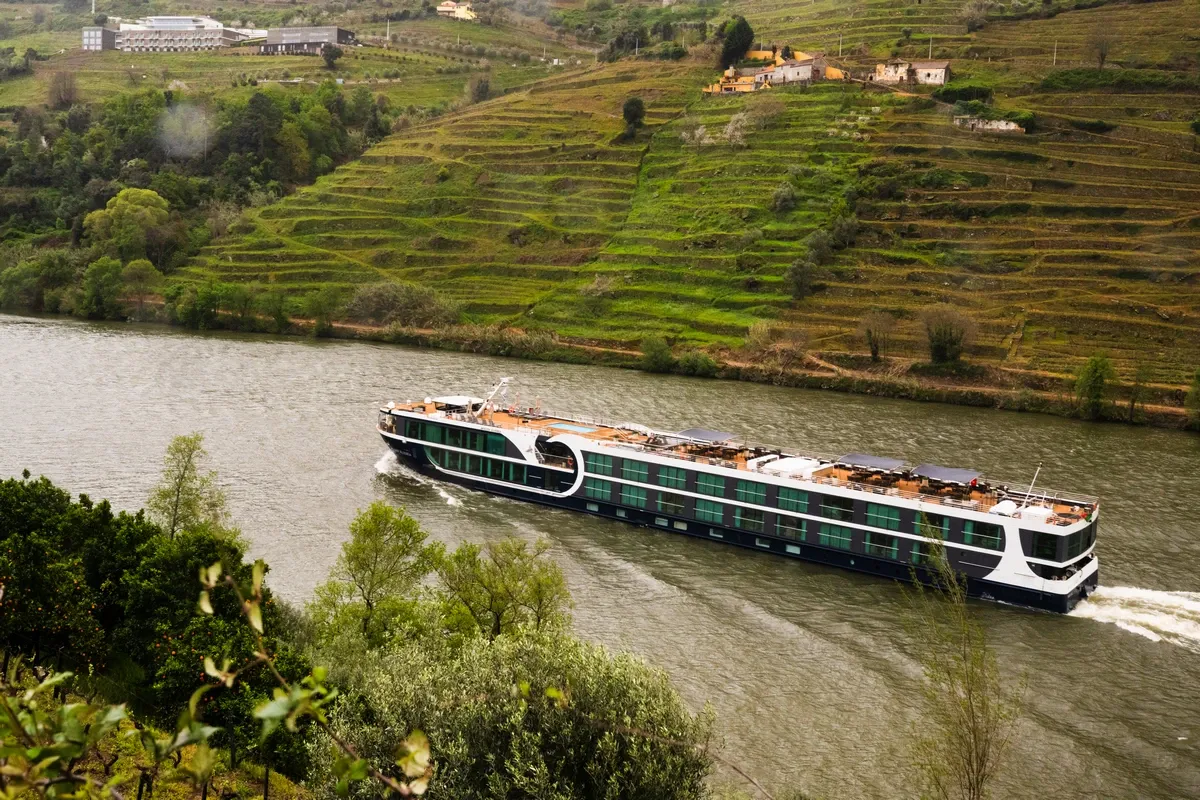 Avalon Waterways cruise ship sailing on a river between mountains