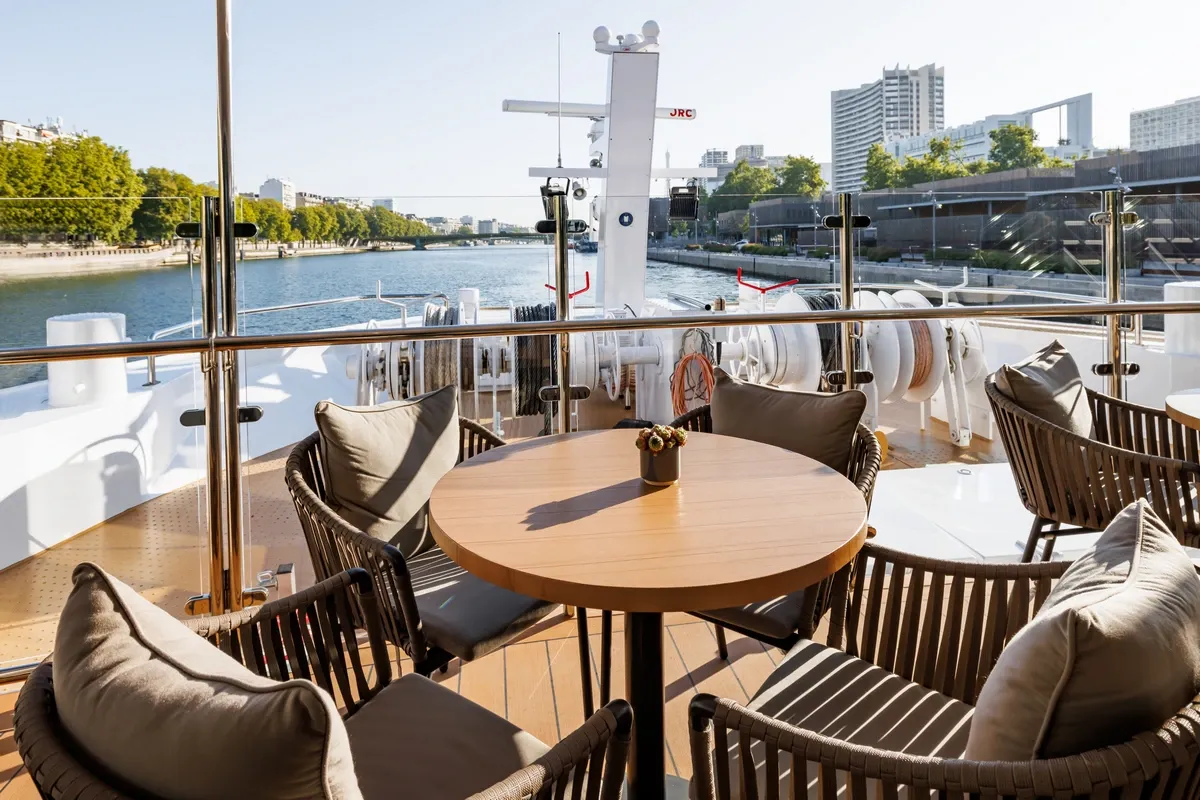 Lounge space on a cruise ship deck with panoramic view to a river
