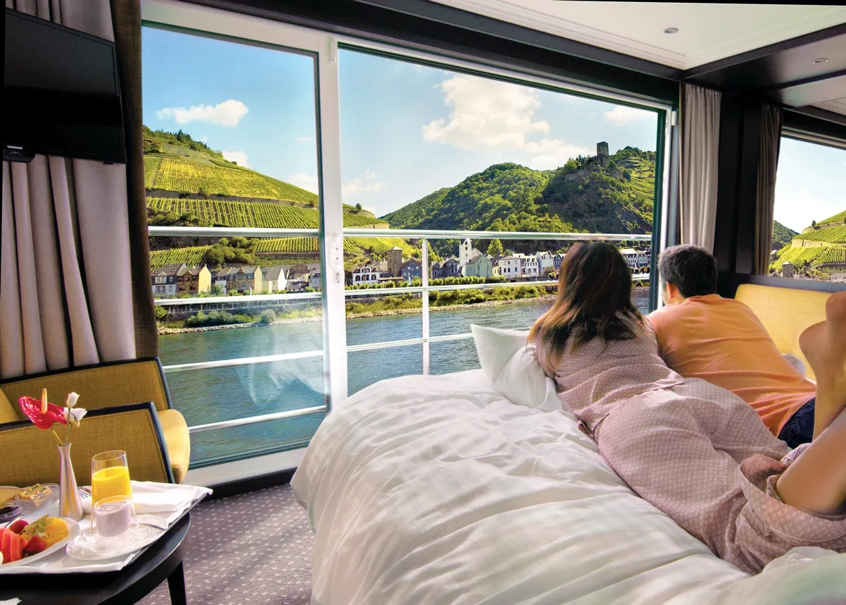 Couple laying in bed watching the river and mountain scenery through the window