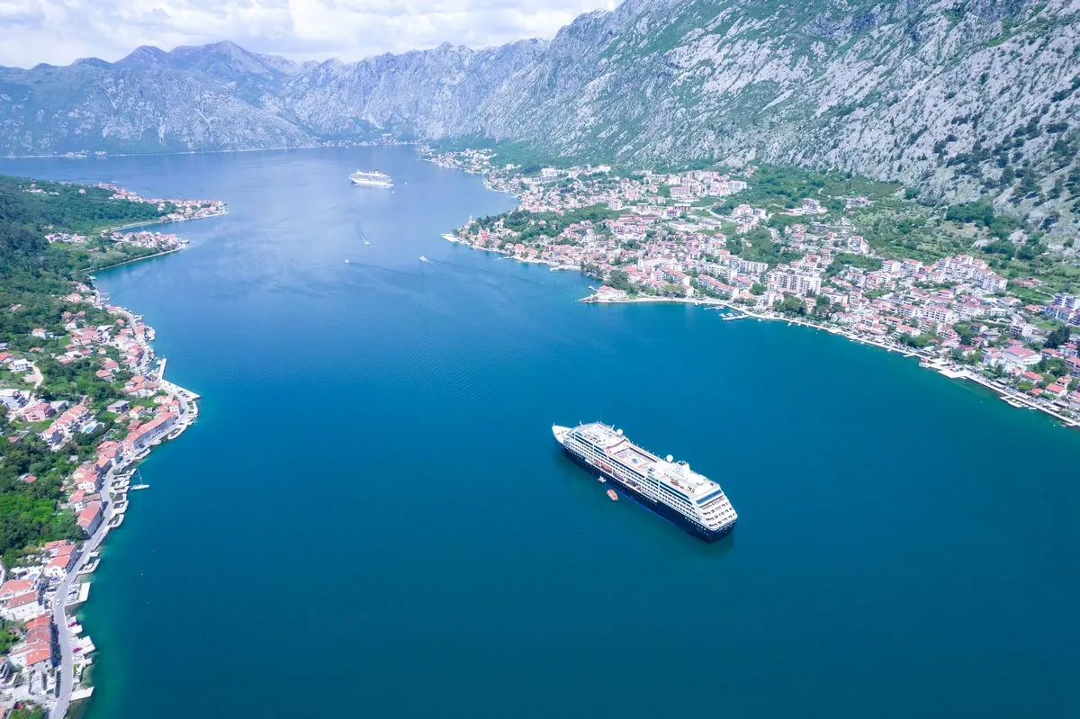 Aerial view of a cruise ship sailing on a river between mountains