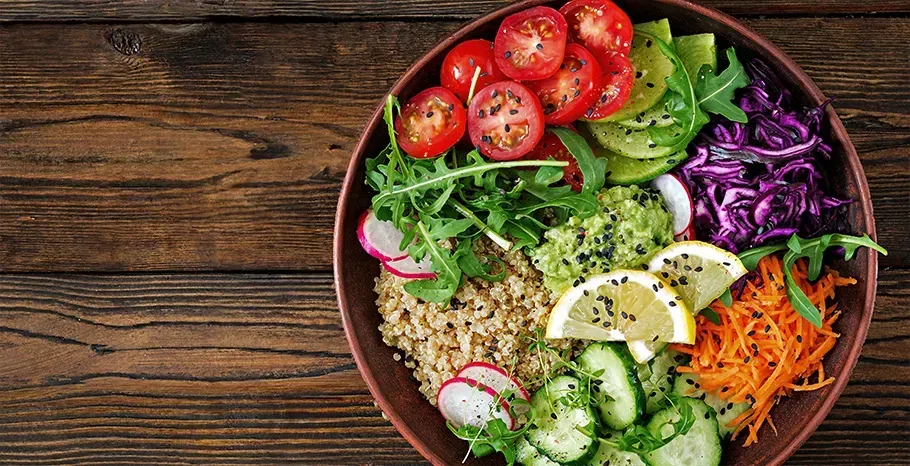 Tomato, quinoa, cucumber and greens salad at a table