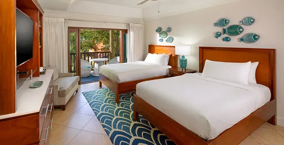 Spacious room with two queen beds and a balcony with view to the resort's garden