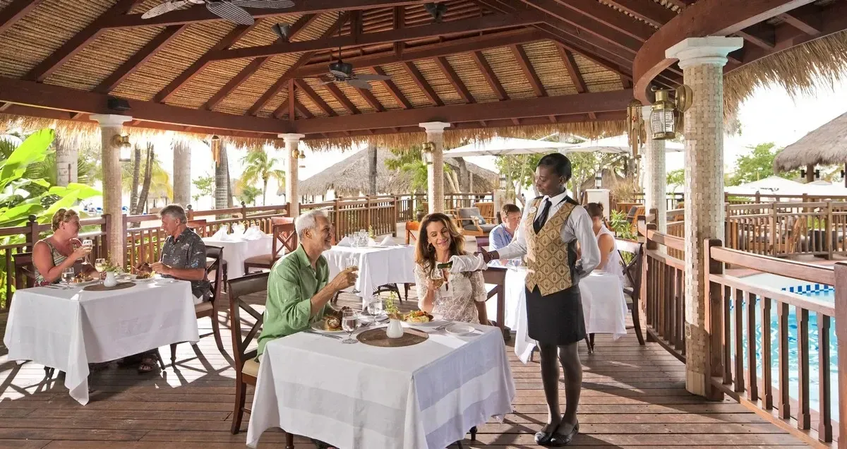 People sitting down at a restaurant with a waitress serving them wine
