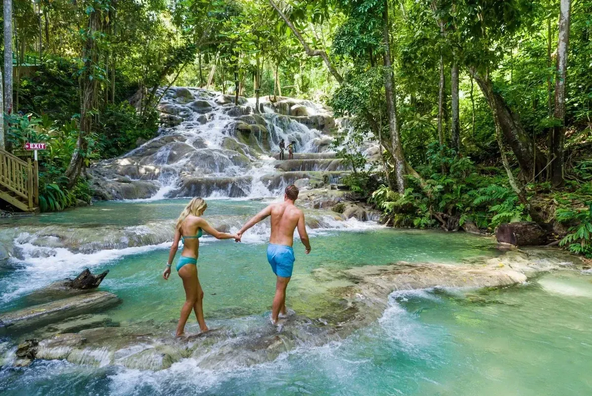 A couple walking next to a waterfall on a tropical scenery