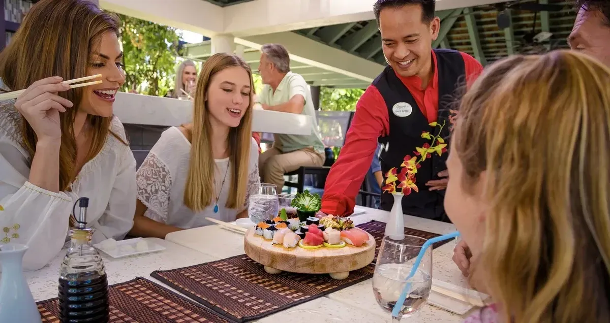 Waiter serving a plate of sushi to a group of friends