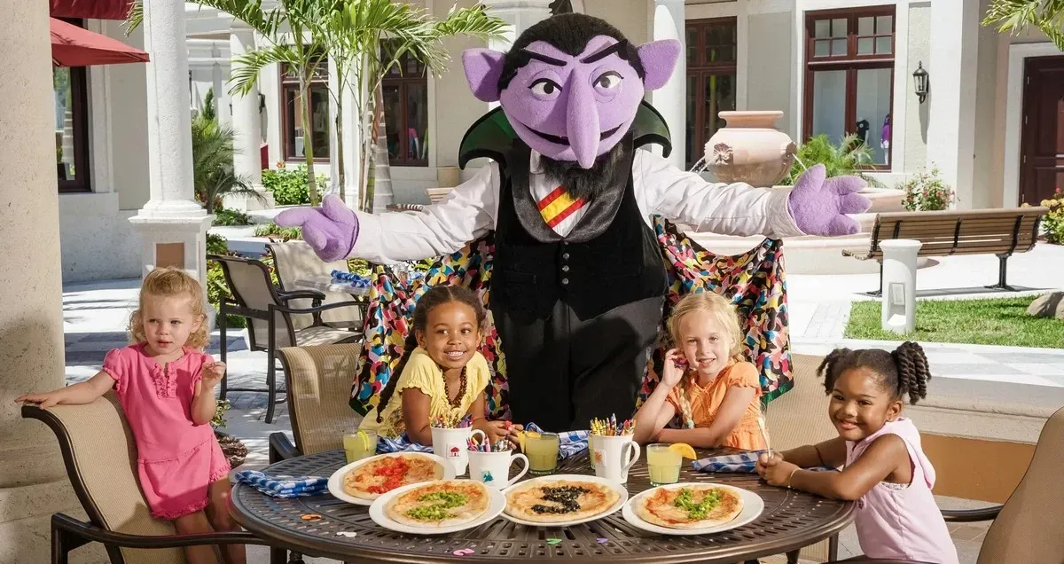 Sesame Street character posing next to two kids