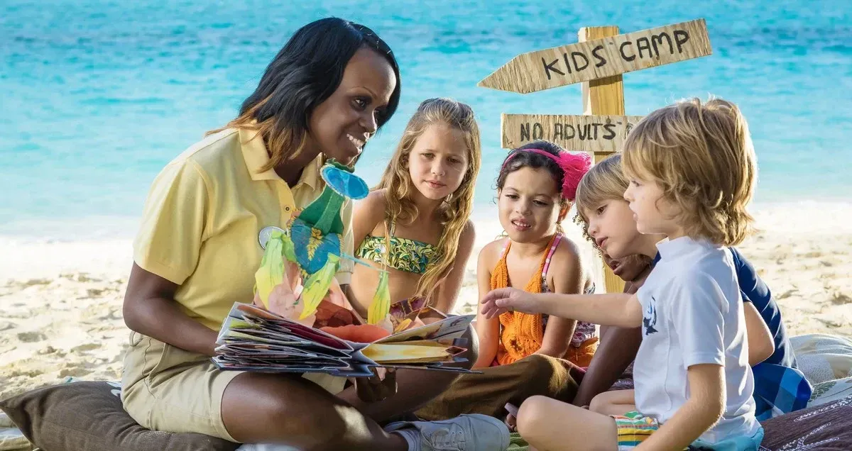 Nanny with a group of kids reading a story at the beach