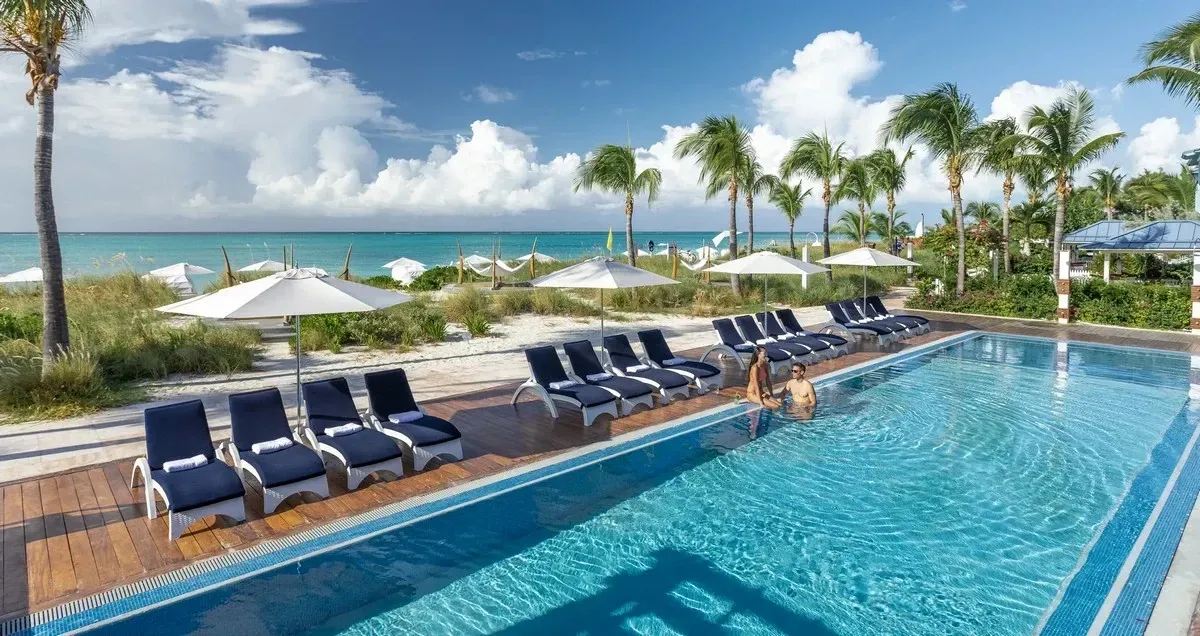 Poolside view with many sunbeds and the beach on the horizon