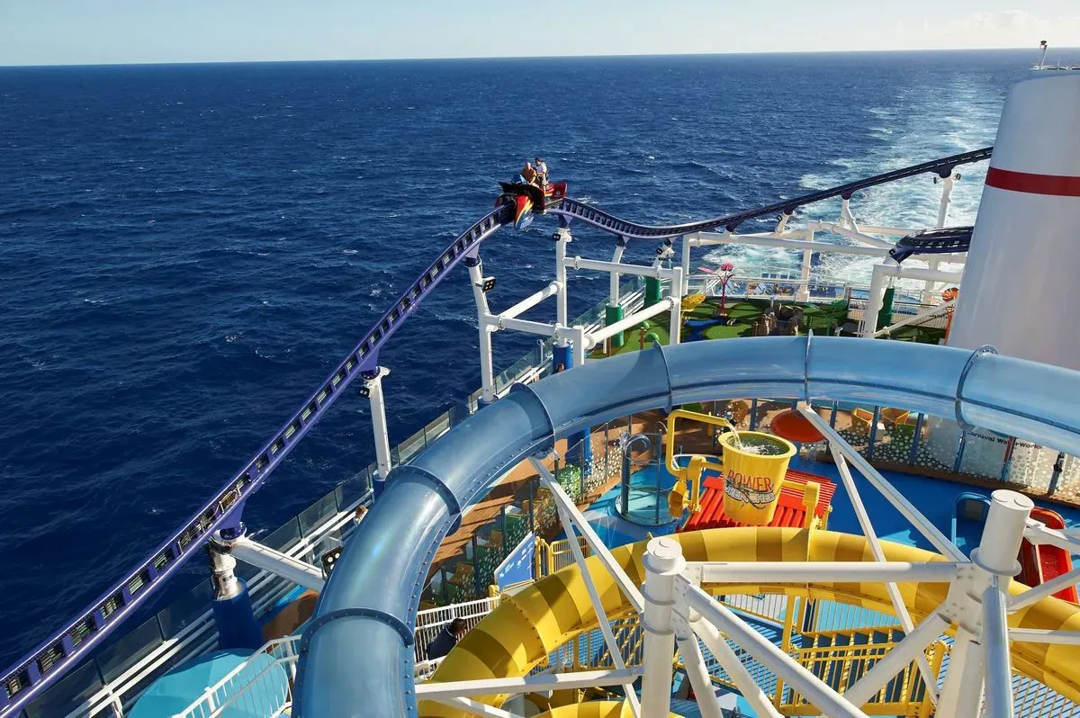 People riding a rollercoaster on the top deck of a cruise ship