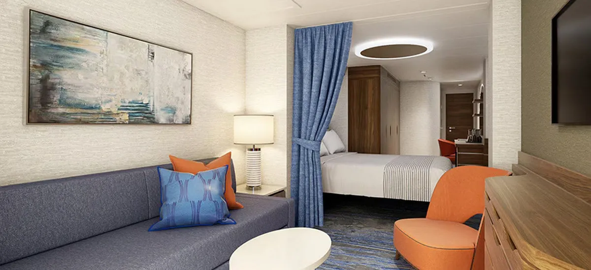 Living space of a cruise ship room with a large bed on the background