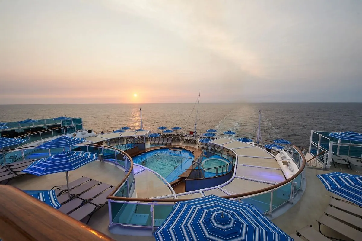 Top deck pool surrounded by sunbeds with views to the ocean