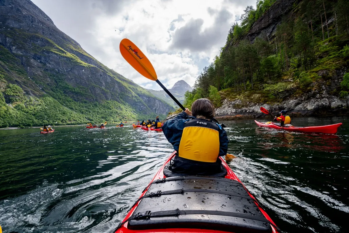 Person doing kayak on a river between mountains