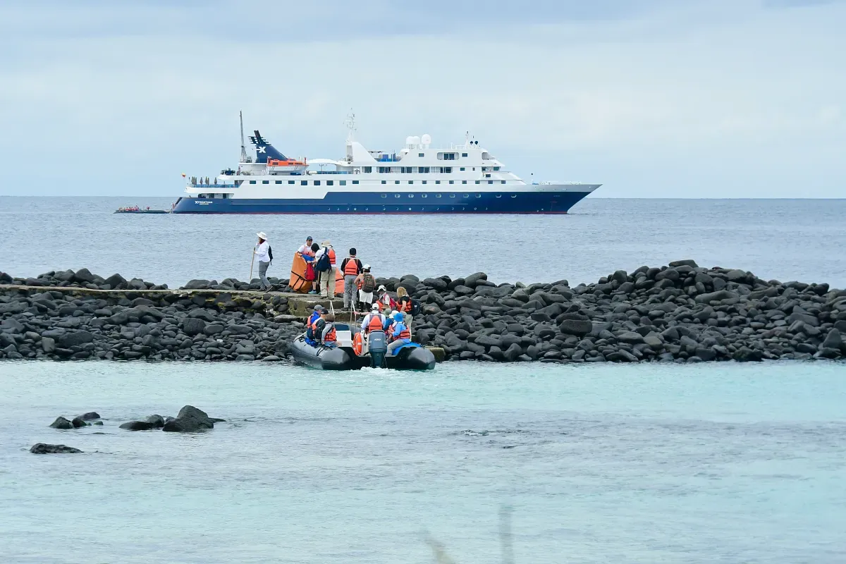 People on a zodiac boat and a cruise ship on the background