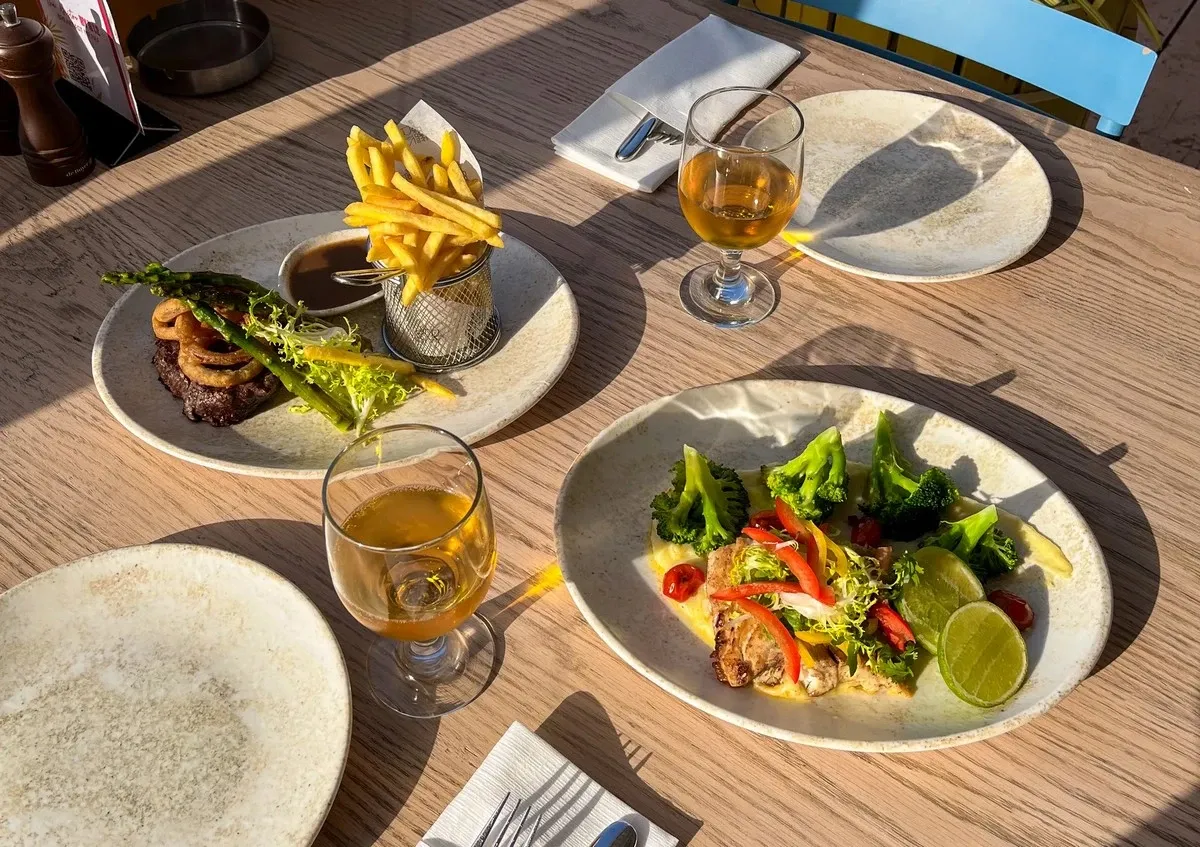 Table with a plate of salad and a plate of steak with fries