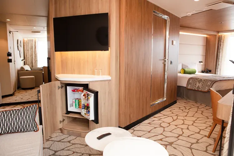 View of a suite with a bed in the background, living space, and a minibar
