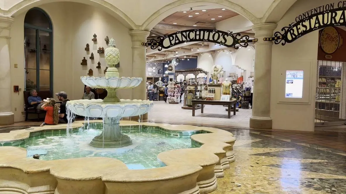 A decorative fountain with cascading water sits in the foreground of an indoor shopping area. The entrance to a store named Panchito's is visible behind the fountain, displaying various items inside.