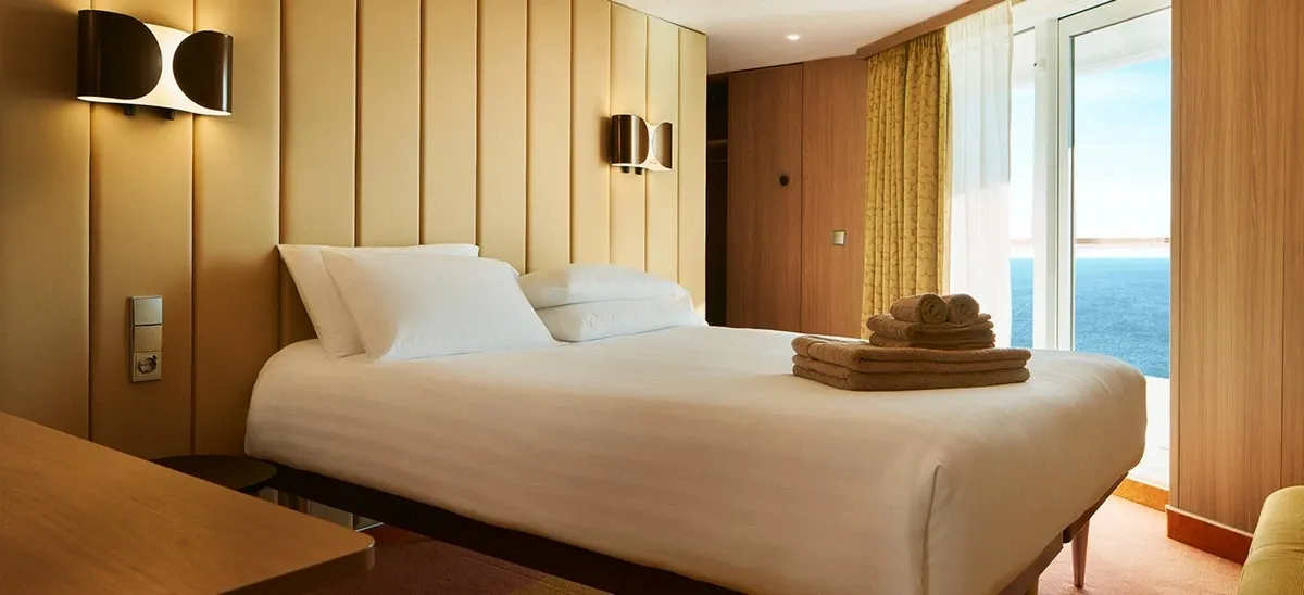 Cruise ship suite with a large bed and views to the ocean