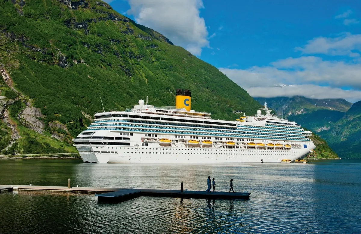 Side view of a cruise ship with mountains on the background