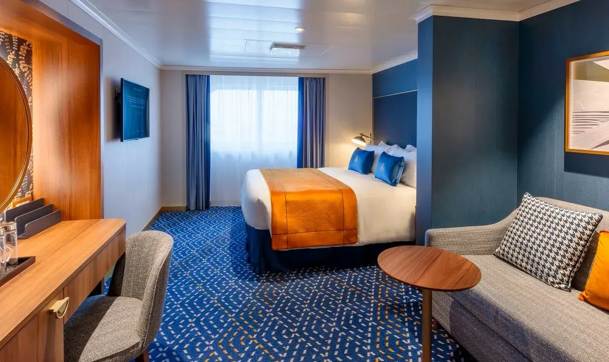 Cruise ship stateroom with a large bed and living space