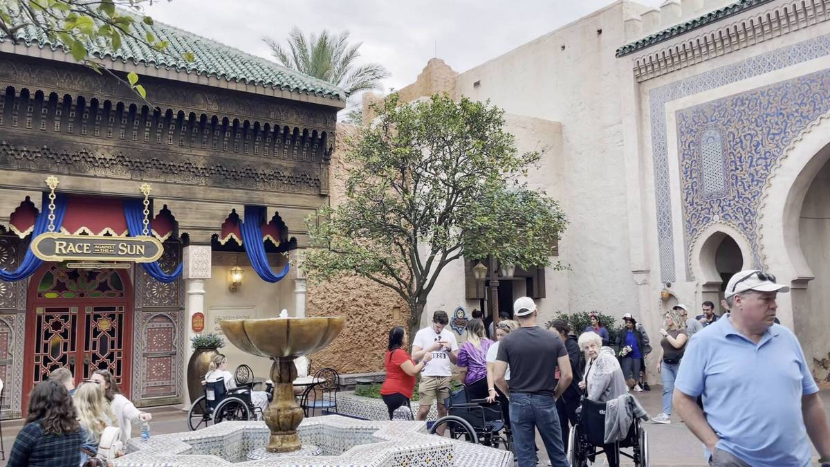 People gathered in a courtyard with a decorative fountain. The building features ornate architecture with a sign reading "Race the Sun" above the entrance.