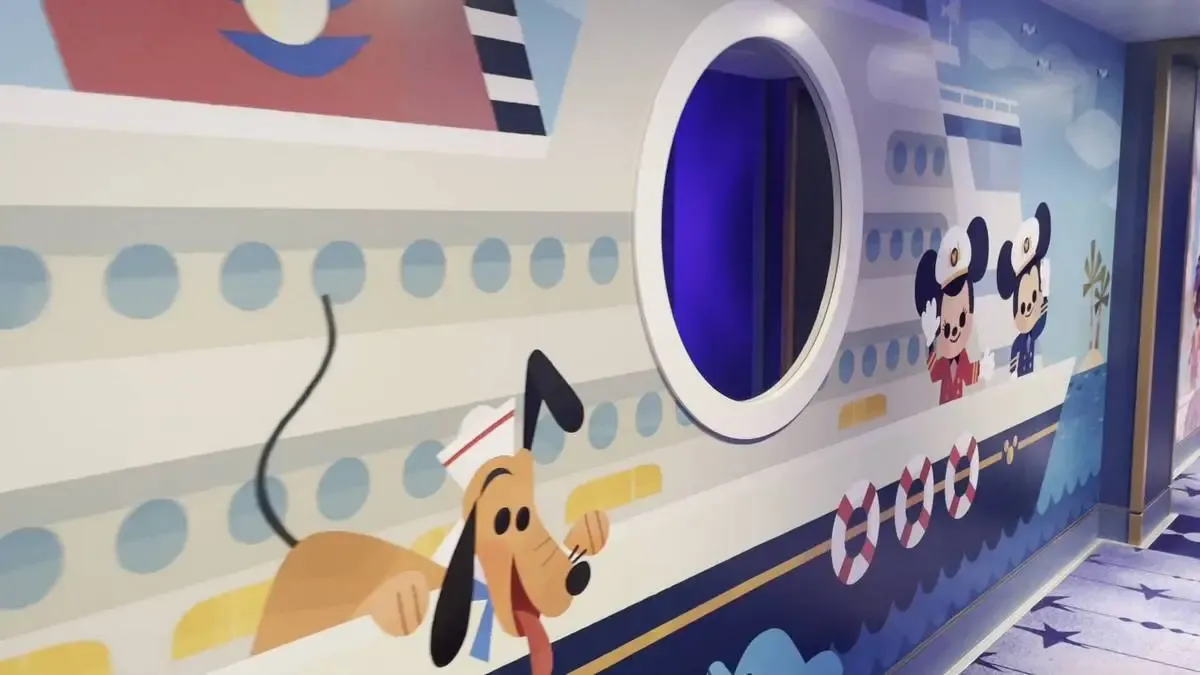 A colorful mural on a wall depicts a cartoon cruise ship with characters resembling iconic animated figures. A round window is integrated into the design, and the scene includes playful elements like a dog wearing a sailor hat, adding a whimsical touch.