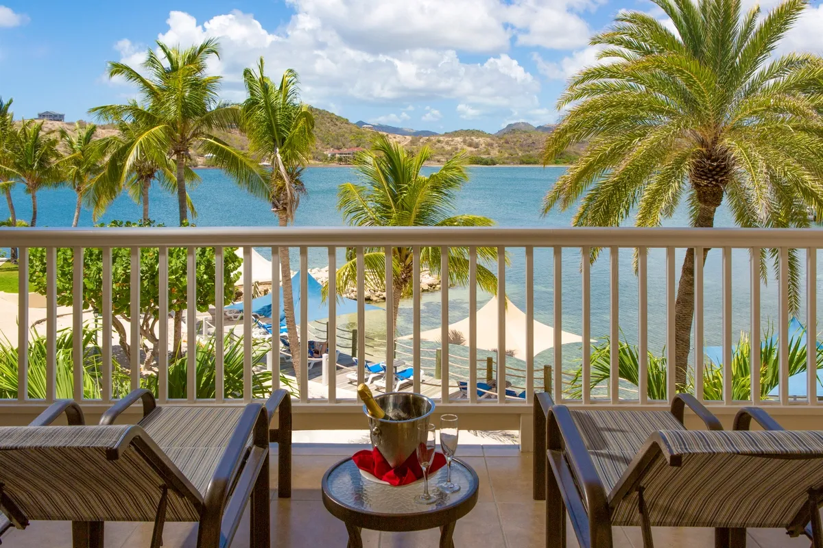 Sunbeds on a balcony with view to the beach next to a line of palm trees