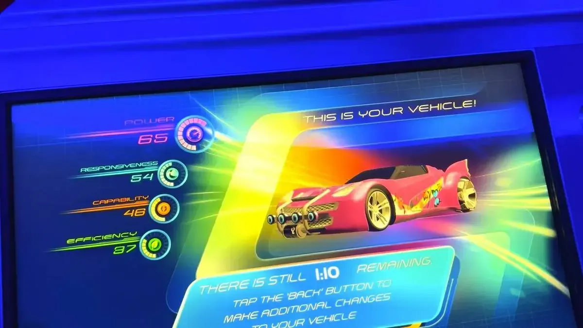 A digital display shows a pink sports car design with sleek features. The screen lists performance metrics and a timer to make changes to the car.