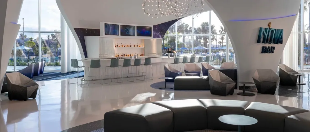 A modern bar area features a curved white counter with stylish gray barstools. The "NOVA BAR" sign is prominently displayed on the wall, adding a contemporary touch to the setting.