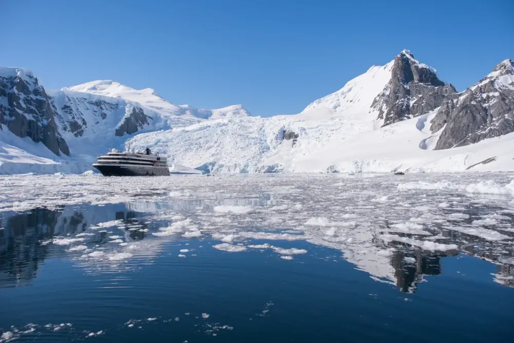 Cruise ship sailing next to a glacier and icy water
