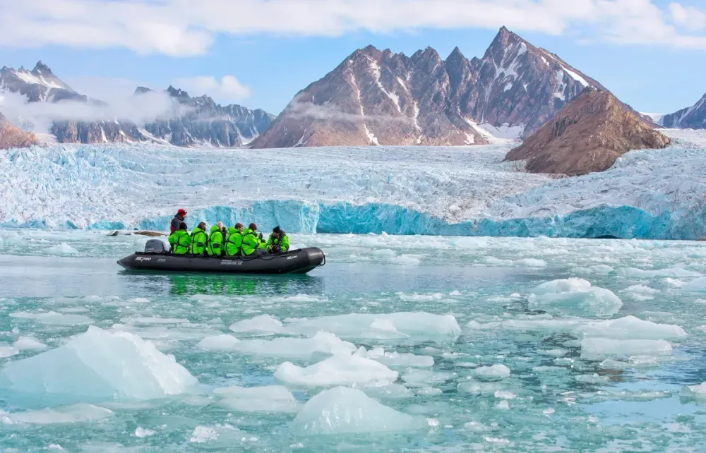 Group of people on a zodiac boat looking at a glacier