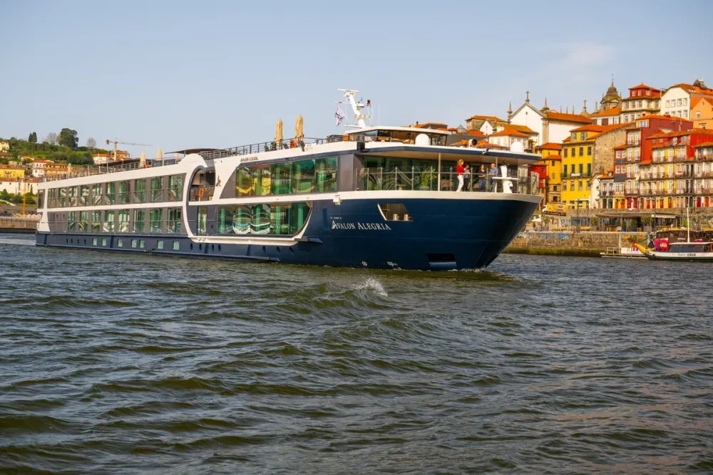 Cruise ship Avalon Alegria sailing on a river next to a city