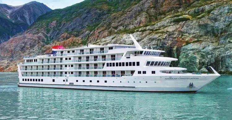 American Constellation cruise ship sailing next to mountains